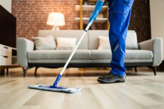 Uma pessoa limpando o chão de uma sala de estar com um esfregão Swiffer