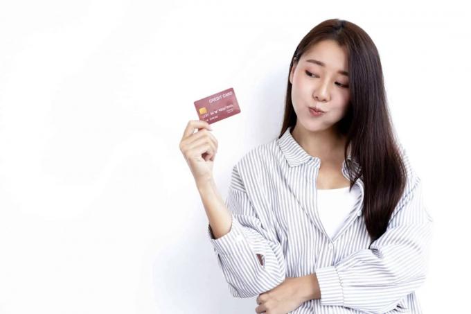 jauna moteris, laikanti kreditinę kortelę baltame fone